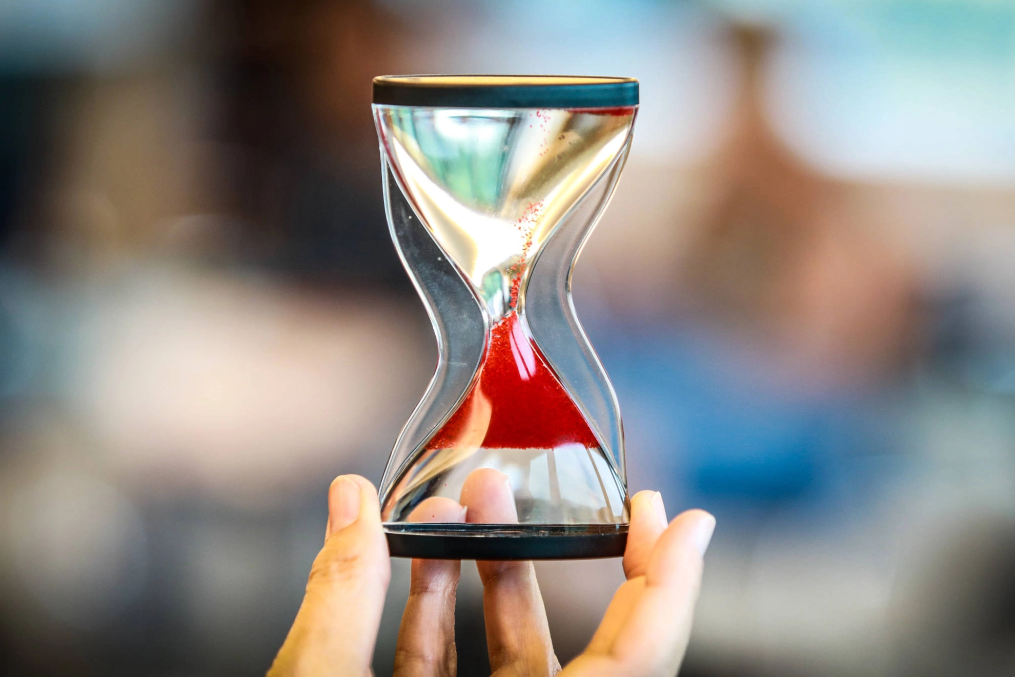 Eine Sanduhr, durch die roter Sand rinnt.